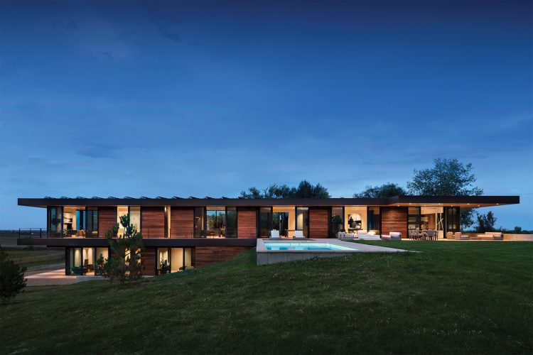 This net-zero home on 40 acres has a unique layout that cantilevers from the sloping hillside, providing a backdrop for the patio, pool, and sweeping landscape.