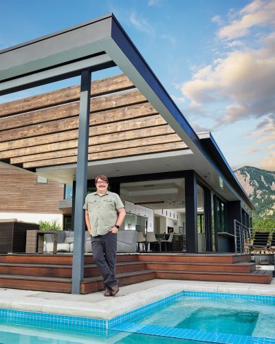 Chris Gray stands in front of an addition he designed for a steep site with a panorama of the Flatirons and Boulder. Large panoramic viewdoors and windows allow the living room, dining room, and kitchen access to the outdoor decks, landscaping, and pool.