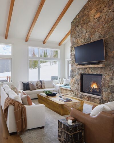 In the great room, the clean and simple lines of the furniture play against the rough stone fireplace.