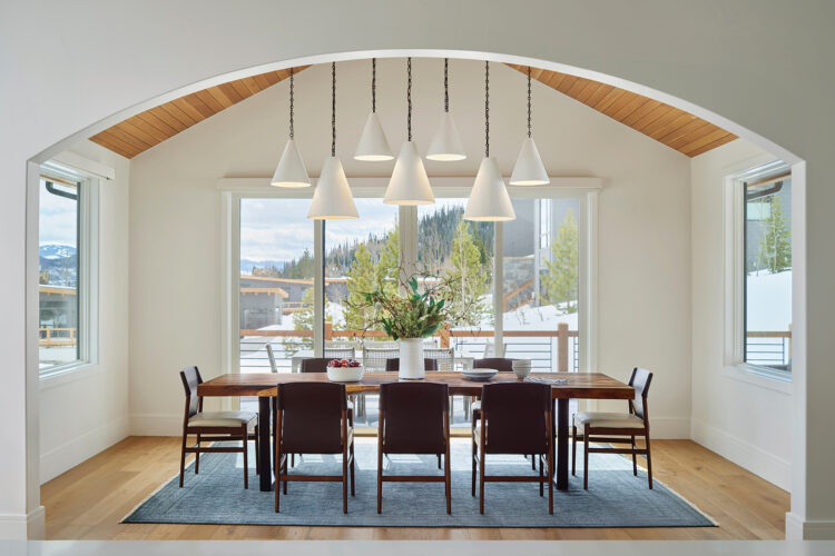 The blue rug softens the stark white, black and light wood design in the dining room, while the tongue-and-groove ceiling and plaster light pendants add texture.