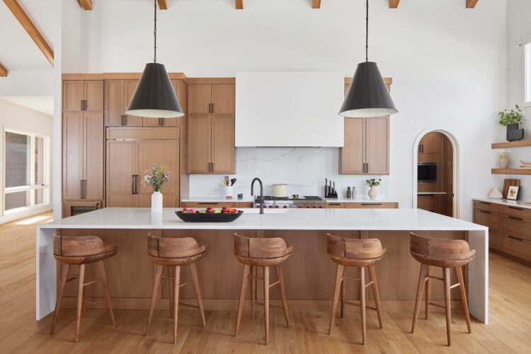The black pendant lighting in the kitchen adds contrast to the white and wood color palette.