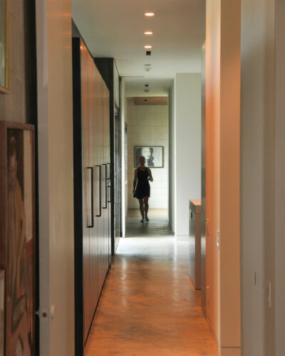 Contemporary home interior featuring a long hallway with polished concrete floors, floor-to-ceiling wood cabinetry, recessed lighting, and minimalist design.