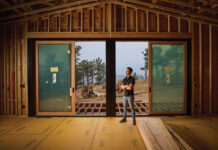 How Fernhill Construction Is Rethinking Luxury Homes in Colorado Colorado custom home builder Alex Molkentin of Fernhill Construction stands inside a home under construction, surrounded by exposed wood framing and large sliding glass doors overlooking a mountain landscape.